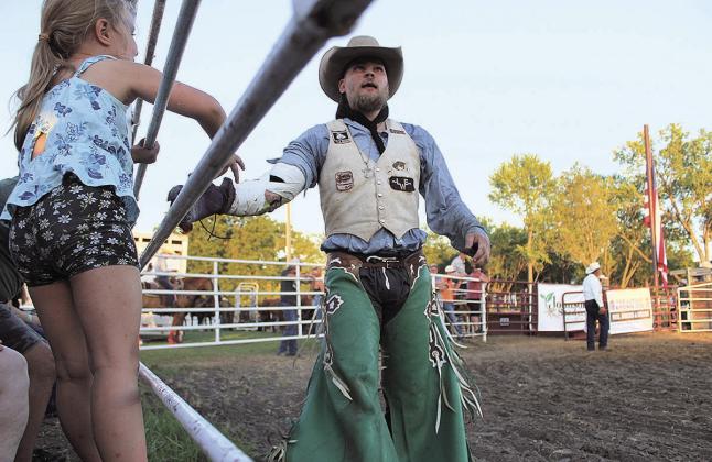A saddle bronc rider high fives his daughter as he gets his score