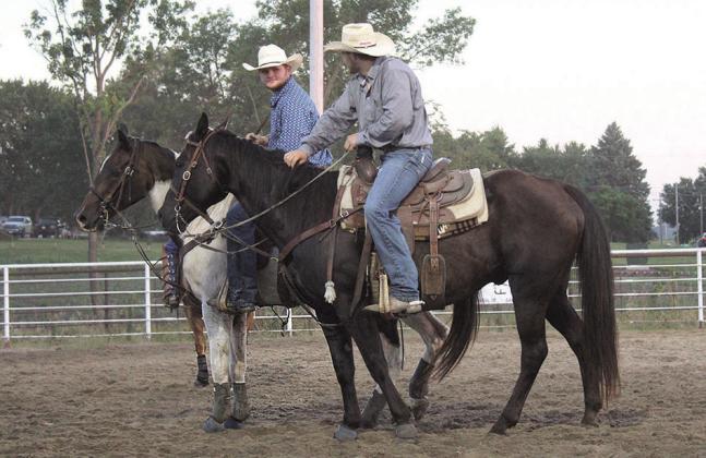 Two steer wrestlers talk while they wait for their steers to be loaded
