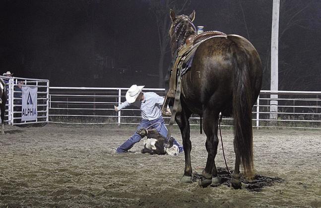 A tie down roper throws his hands in the air to signal he has successfully tied three feet on his calf.
