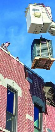 Dave Pope waits on the roof of the Cornerstone building as the NPPD crew moves a new heating and air condition unit into place- Republican photo