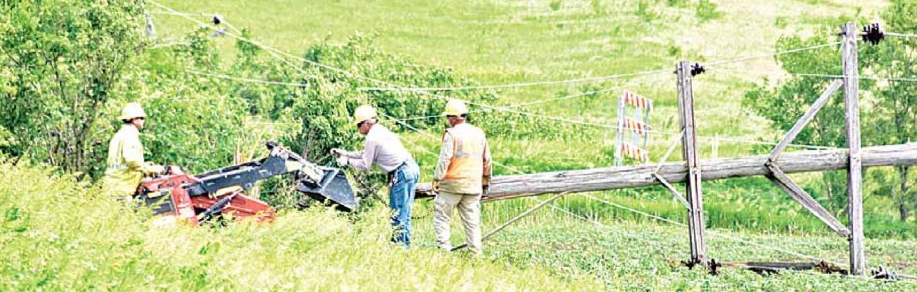 NPPD crews work to drag six down power poles out of a field. The poles were knocked down in the storm June 9. Ray Kappel/Republican