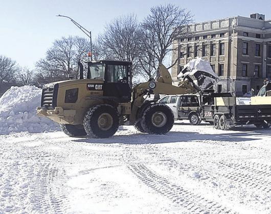 Above: Pawnee City workers cleared snow off the streets on Monday while Below: Ron Puhalla cleared the three foot snow dift in front of the newspaper office just in time for Betty Davis to come to work.
