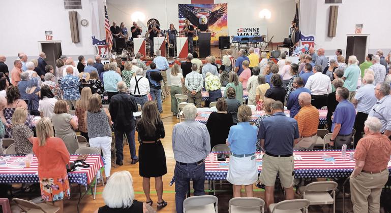 Event attendees stand for the National Anthem