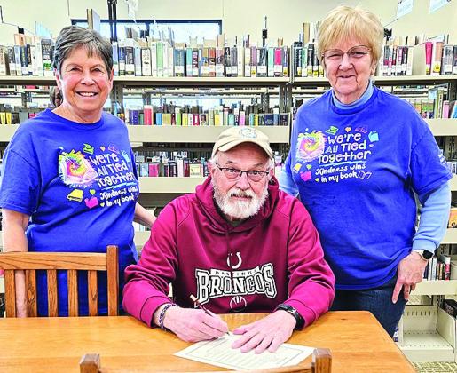 Mayor Charlie Hatfield (middle) signs a proclamation for National Library week as Patty Rice (left) and Lola Seitz (right) look on.