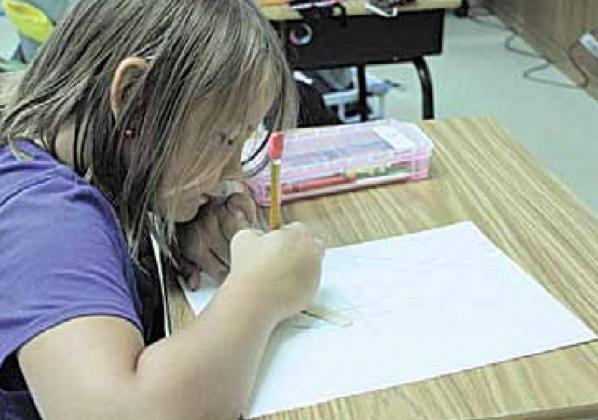 3rd grader Braxton Eagleburger tracing his popsicle stick in creating his optical illusion artwork.
