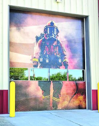 Garret (on the Scissor Lift) and Dustin (on the Ground) from Yellow Frog Graphics are prepping the fire house doors for the door wrap decals. The finished product will be similar to a mural. An American flag will span the doors bearing the words 'Pawnee City Fire Department'