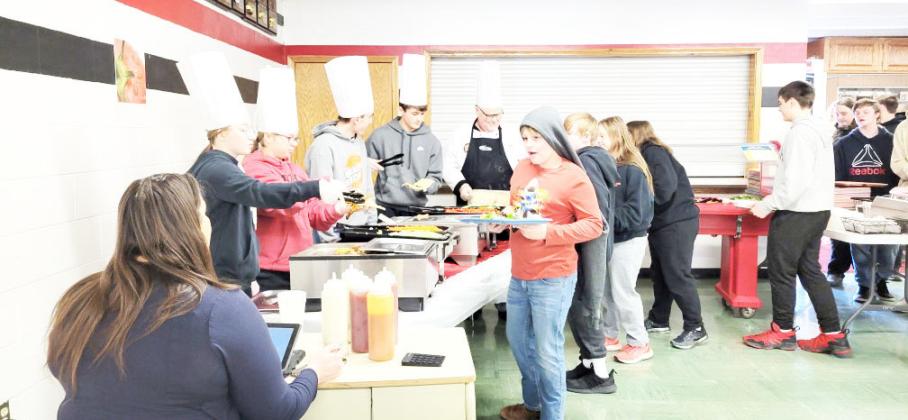 Students Kaylee Turnbull, Deneille Gyhra, Norman McHenry and Wyatt Blank helped Chef Brian dish out the Harissa Chicken Sandwich.