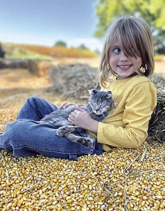 Arya Schlund holds a kitten while playing in the corn patch.