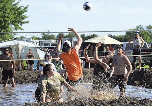 Mud volleyball players spike the ball over the net Photo byAva Meints