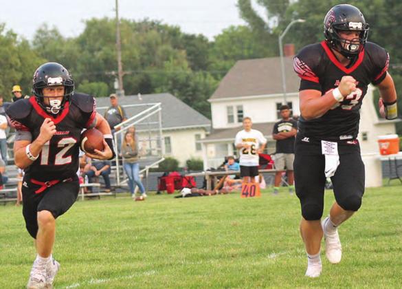 Pawnee City’s Andy Maloley (#12, left) takes off on a touchdown run early in the game with teammate Simon Osborne (#33 right) leading the way. Paula Jasa/Republican