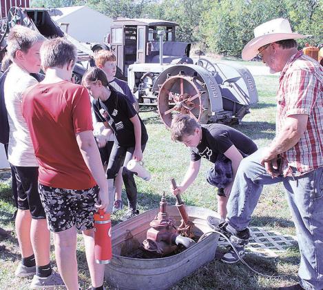 Student Mason pumps water as his friends look on