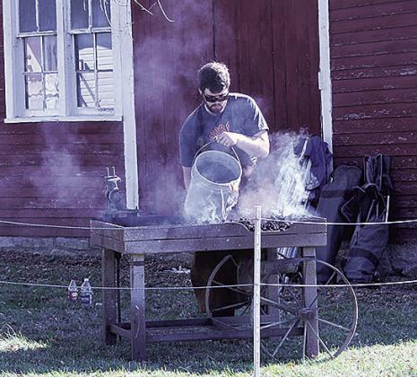 A Pawnee City Historical Society volunteer cleans a charcoal grill