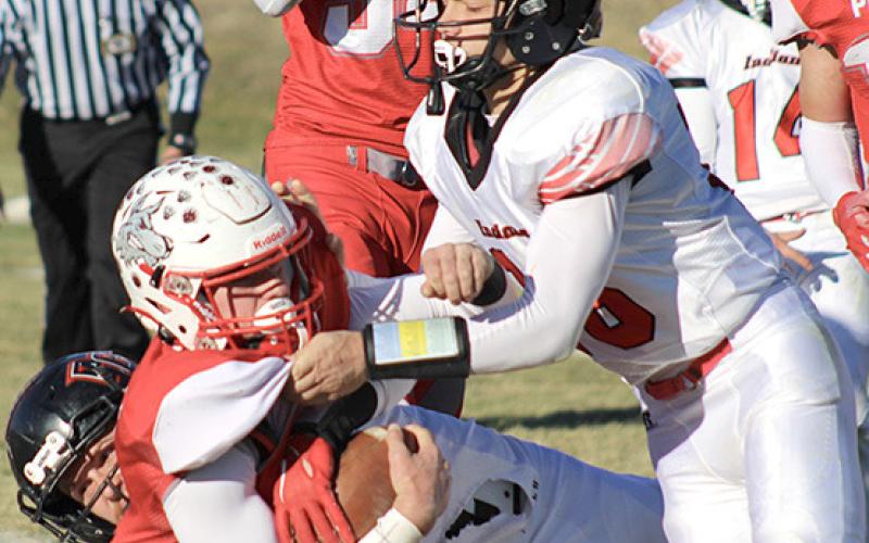 P.C.’s Anthony Kling (#16, right) helps make a tackle against Potter-Dix on Friday. Kling had 10 tackles and a fumble recovery in the game. photo courtesy of Jamie Maloley