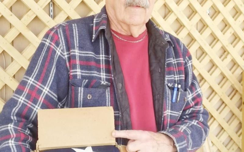 Picture of Lee Malmos attached when donated the cardboard box with the flag and other mementos.