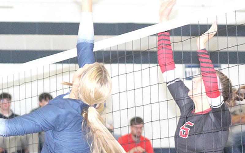 HTRS’ Laramie Glathar (left) tips the ball over a Meridian player in Thursday night’s match. Glathar had 45 set assists, 1 kill and 1 block at the net. Paula Jasa/Republican