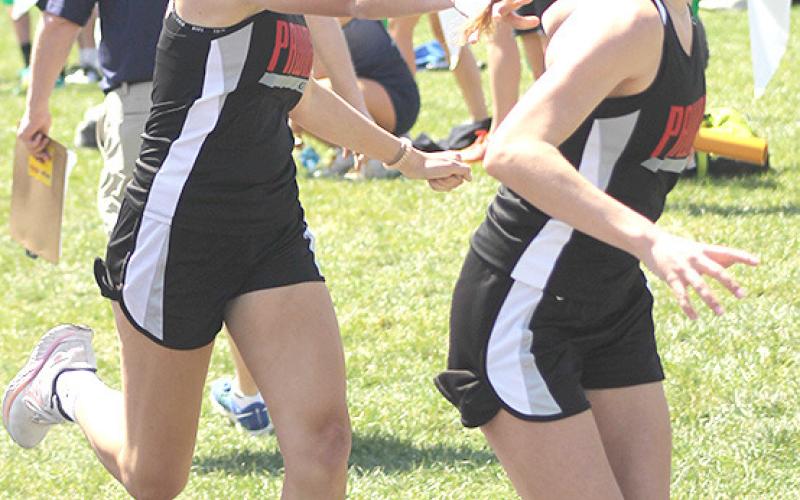 P.C.’s Madelyn Osborne (left) hands off to Emily Lytle (right) in the last leg of the 3200 M. relay event. Paula Jasa/Republican