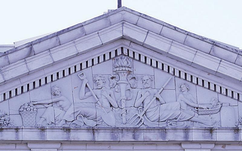 The pediment above the colossal Corinthian columns of the north portico. “Dentils” (small repeating blocks for ornamentation) run above and below it, “Triglyphs” (the four small blocks with grooves) anchor the triangular gable, and within the triangle is a terra cotta sculpture with interesting figures.