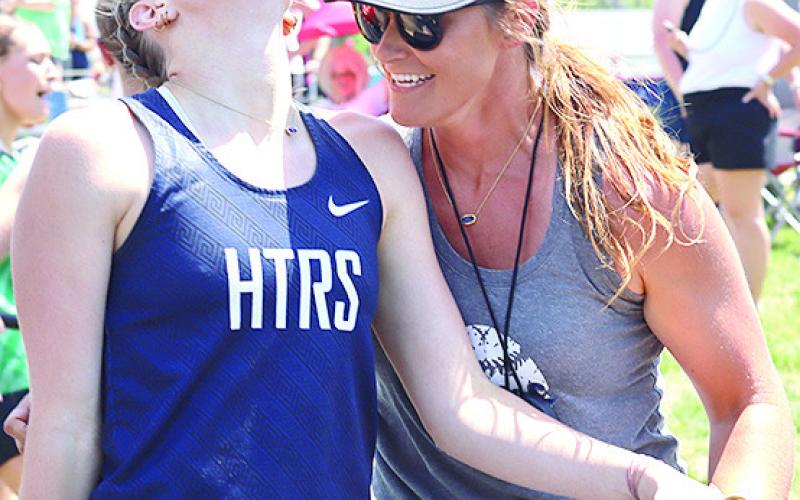 HTRS’ Makena Dunlap gets a helping hand from a coach at the end of the 3200 M. Relay which they won.