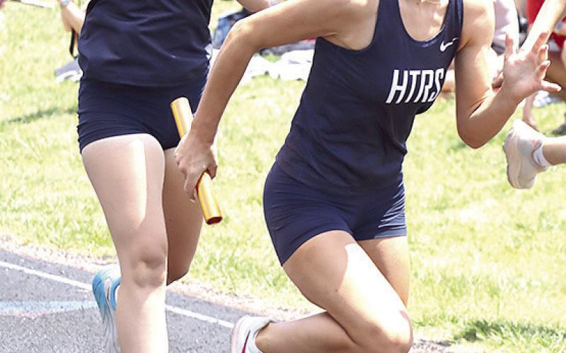 HTRS’ Lillian Bowen receives the baton from teammate Eden Duryea and goes for gold in the 3200 M. event. The Lady Titans were clocked at 10:21.75.