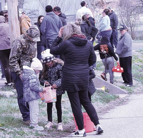 Above: A family gathers to check out their loot. Top left: A girl races to get in line to receive her paper eggs. Top right: A mother and son search the lawn for hidden eggs Bottom: Children line up to receive paper eggs. These eggs direct children to local businesses which will hand out extra prizes.