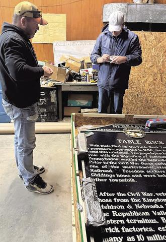 Village maintenance worker John Ticnor and Kim Vrtiska, president of the Table Rock Historical Society, make sure that all of the hardware for attaching the marker to its poles was included in the shipment.