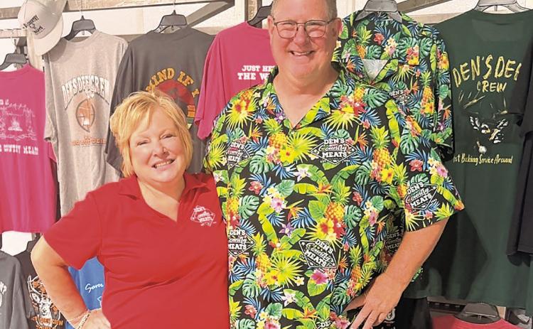 Proprietors Kim &amp; Dennis Schaardt in front of a display of Den’s Country Meats t-shirts. Given some hints about how to do something “besides just stand there,” Kim Schaardt asks, “So you want some sass?!” Dennis, he’s not sassy, he’s just pleased and delighted to be in the business for so long and still going strong.