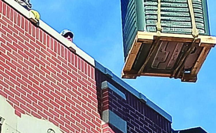 Dave Pope waits on the roof of the Cornerstone building as the NPPD crew moves a new heating and air condition unit into place- Republican photo