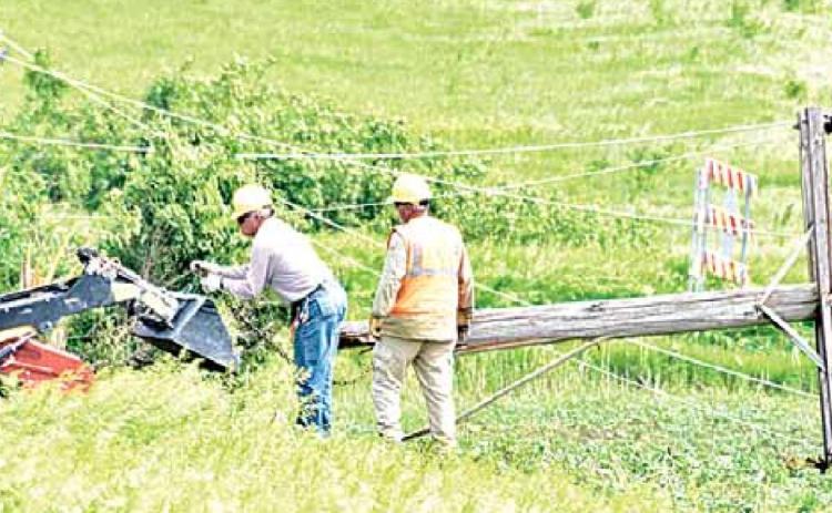 NPPD crews work to drag six down power poles out of a field. The poles were knocked down in the storm June 9. Ray Kappel/Republican