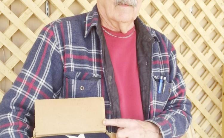 Picture of Lee Malmos attached when donated the cardboard box with the flag and other mementos.