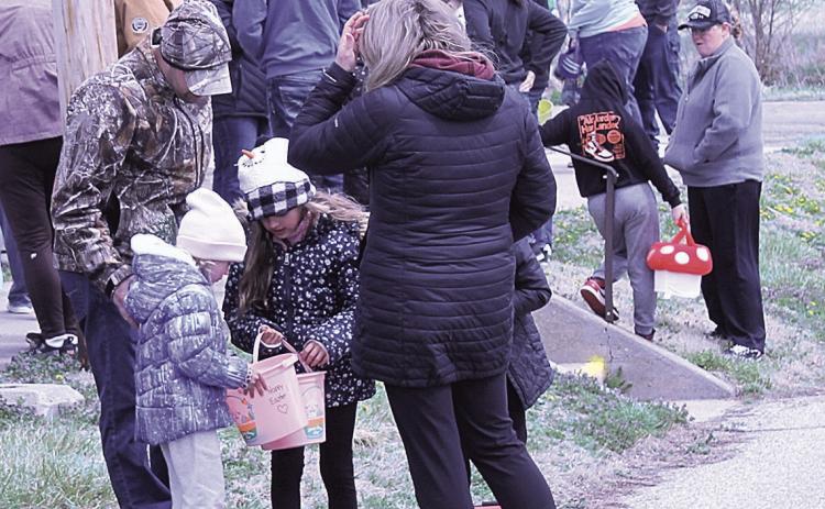 Above: A family gathers to check out their loot. Top left: A girl races to get in line to receive her paper eggs. Top right: A mother and son search the lawn for hidden eggs Bottom: Children line up to receive paper eggs. These eggs direct children to local businesses which will hand out extra prizes.