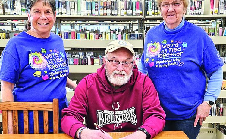 Mayor Charlie Hatfield (middle) signs a proclamation for National Library week as Patty Rice (left) and Lola Seitz (right) look on.