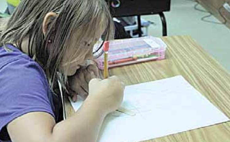 3rd grader Braxton Eagleburger tracing his popsicle stick in creating his optical illusion artwork.