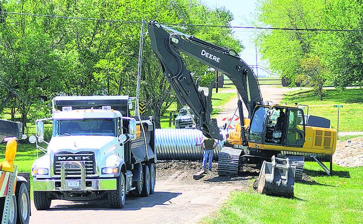 Workers install a wider tube to prepare to expand the fairgrounds road to a two lane road per the street plan.