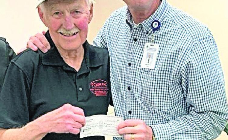 Dr. Rick Jackson, retired, hands a check to John Werner which pays off the loan for the new ambulance.