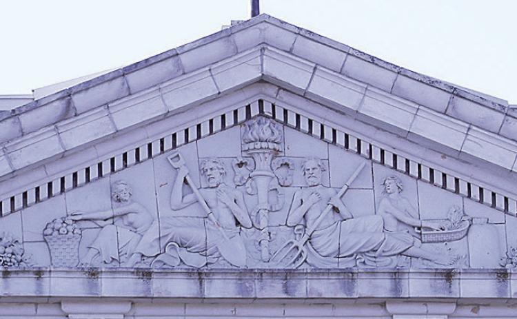 The pediment above the colossal Corinthian columns of the north portico. “Dentils” (small repeating blocks for ornamentation) run above and below it, “Triglyphs” (the four small blocks with grooves) anchor the triangular gable, and within the triangle is a terra cotta sculpture with interesting figures.