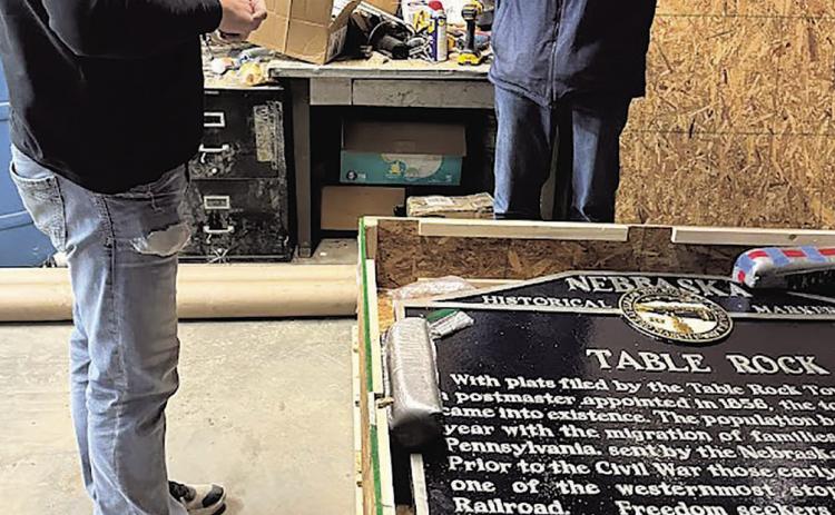 Village maintenance worker John Ticnor and Kim Vrtiska, president of the Table Rock Historical Society, make sure that all of the hardware for attaching the marker to its poles was included in the shipment.