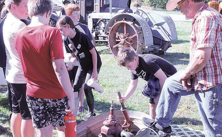 Student Mason pumps water as his friends look on